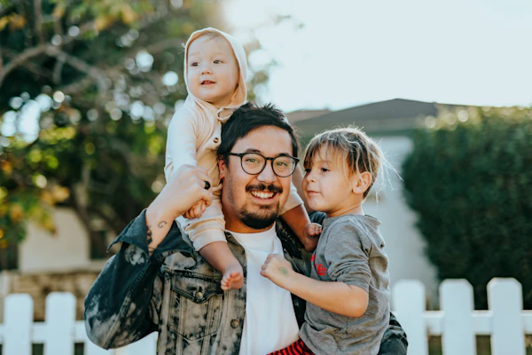 Pai sorrindo com os dois filhos no colo